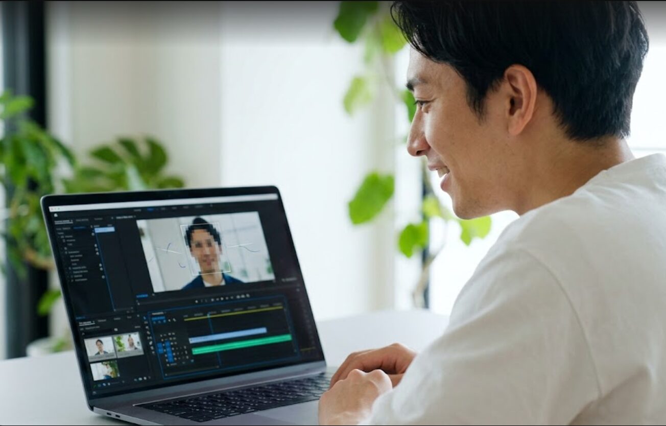 パソコンでAIトラッキング機能付きの動画編集ソフトを使う日本人男性。自動でモザイクが追従する様子を見て、笑顔で快適に作業している。
