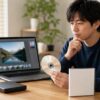 Photoshop Elements旧バージョンのDVDと写真編集画面を見ながら、再インストール方法を確認する日本人男性
